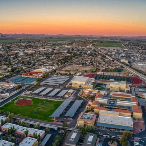 Aerial view of a suburban area at sunset with residential and school buildings.