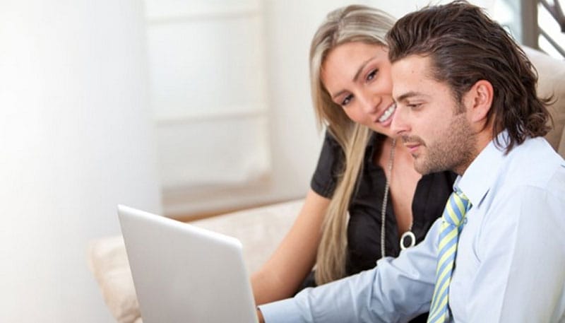 Two people looking at a laptop screen together.