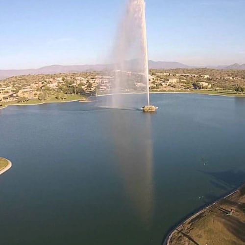 A large fountain spraying water high into the air in the center of a lake in Fountain Hills, Arizona.