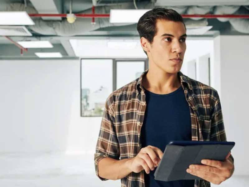 a Property Manager holding a tablet while looking to the side in an office environment.