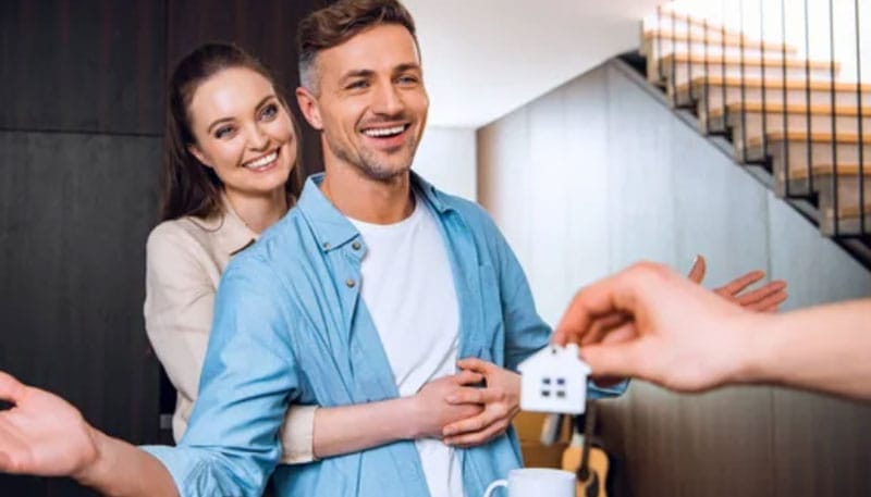 A smiling couple receives keys while seeming to be engaged in a real estate transaction.