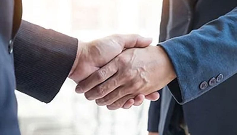 Two individuals in professional attire shaking hands.