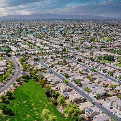 Aerial view of a suburban neighborhood in Avondale, Arizona with rows of houses, streets, and a green park area.