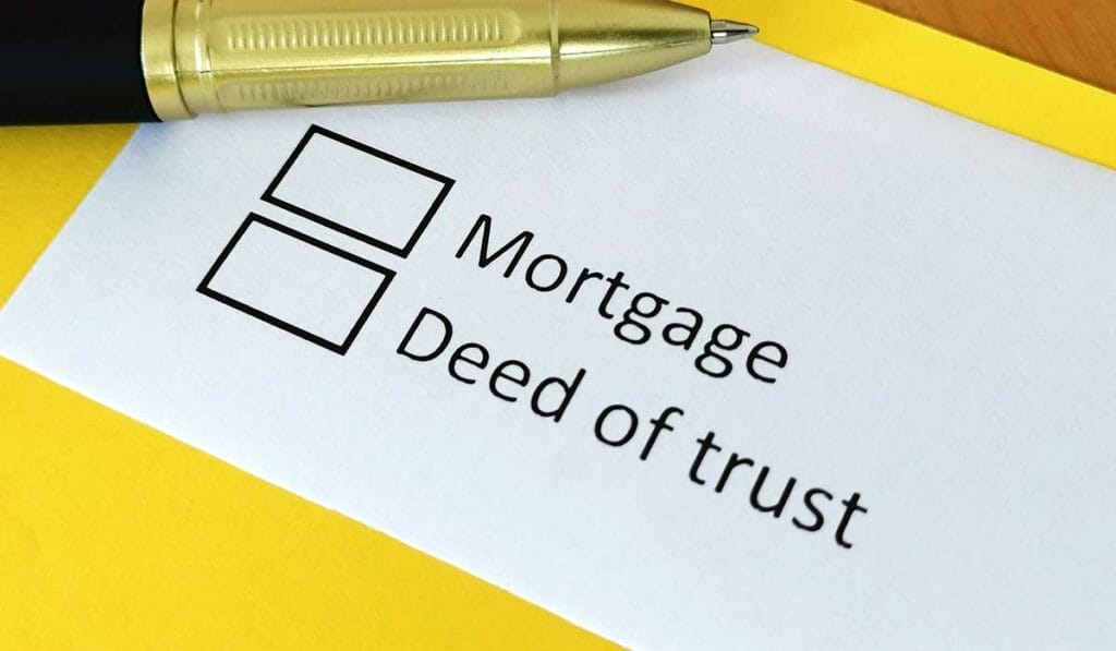A pen rests on a paper labeled with checkboxes for "Mortgage" and "Deed of trust" on a yellow folder.