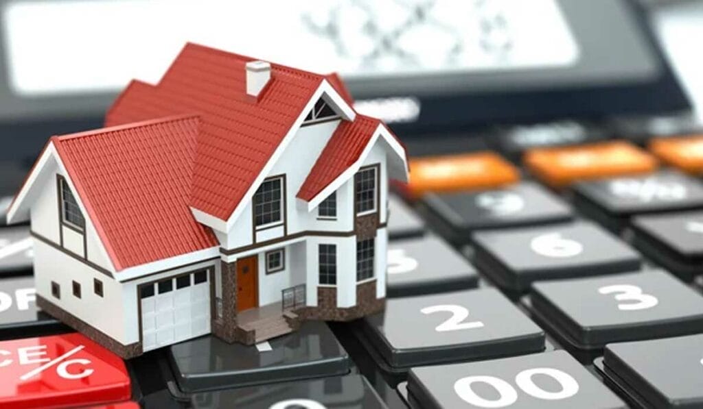 A small house model sits on a digital calculator, representing real estate and mortgage calculations.